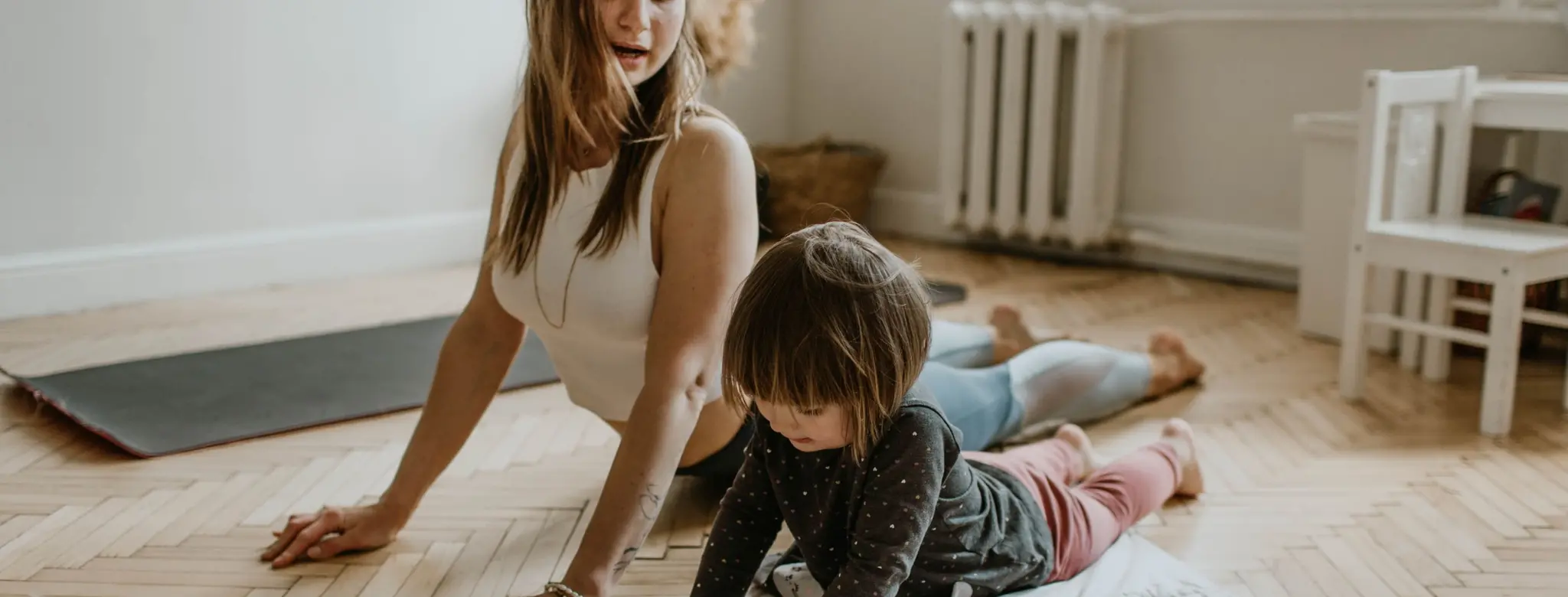 Woman doing yoga with her young daughter at home