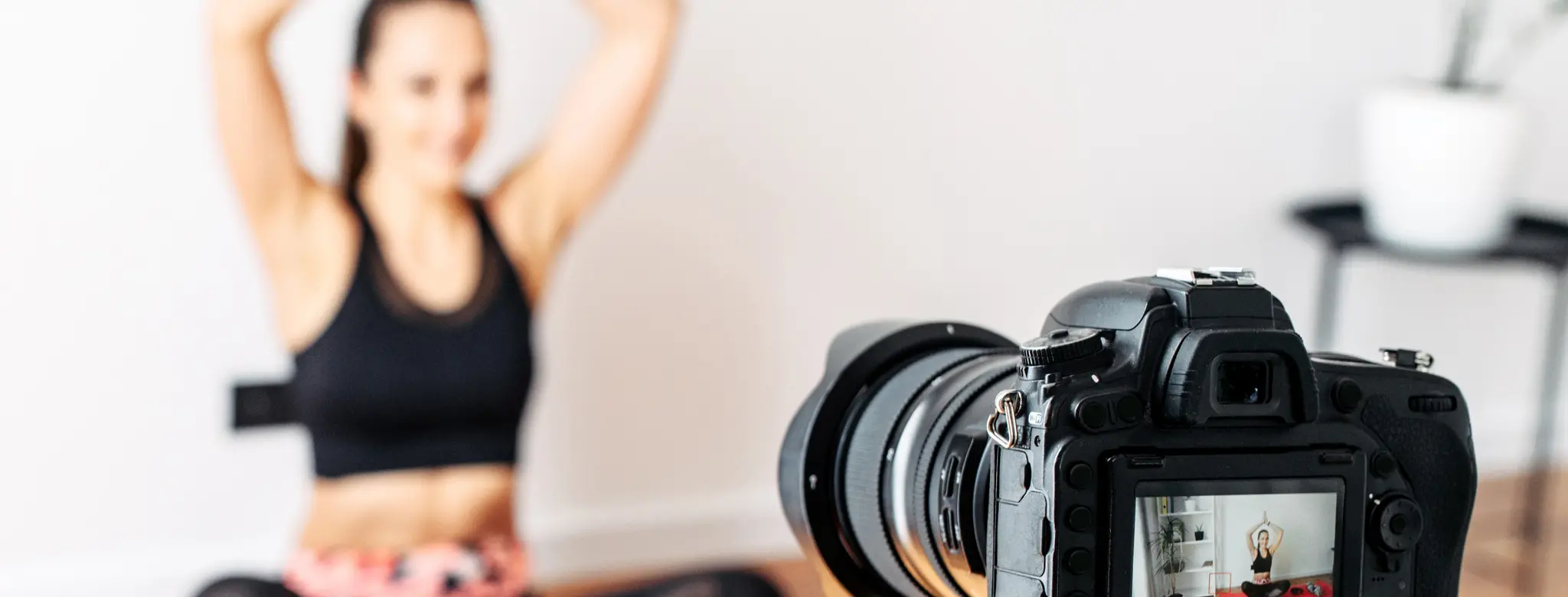 Fitness instructor filming a workout video in front of a camera on a tripod
