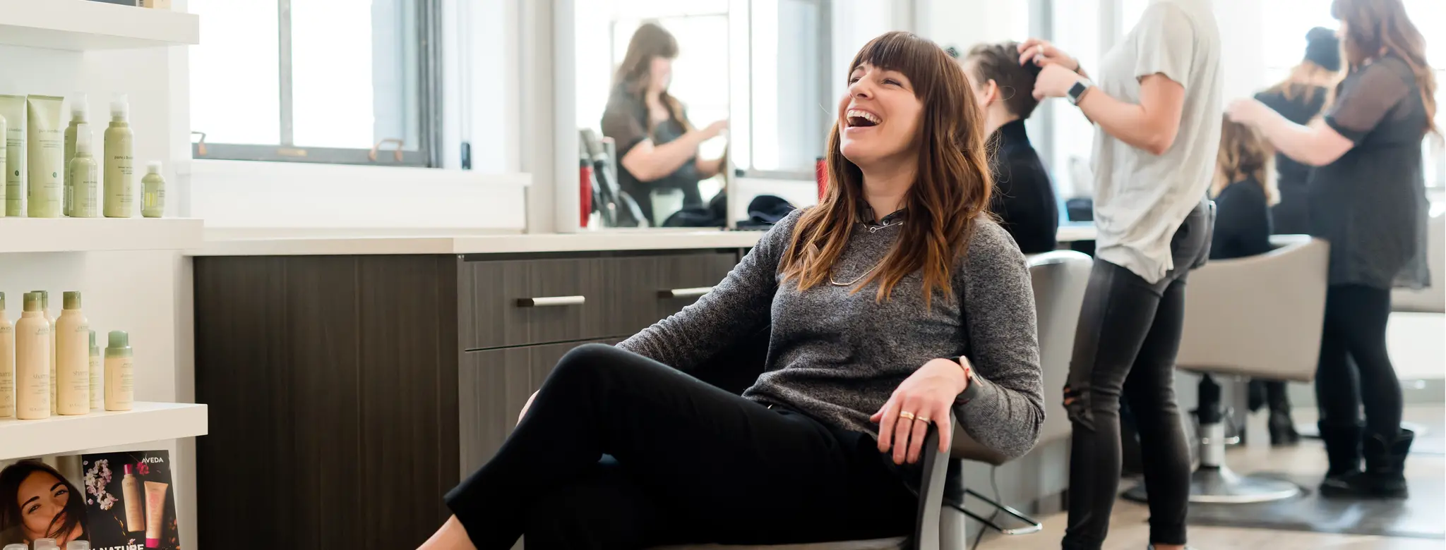 woman sitting in chair laughing in salon