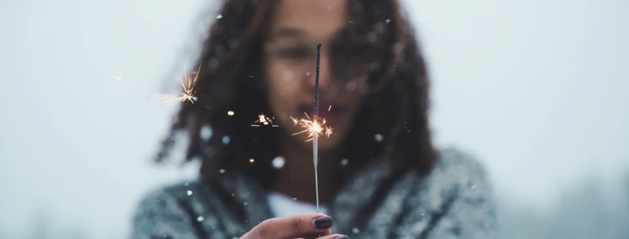 woman in sweater holding sparkler outside