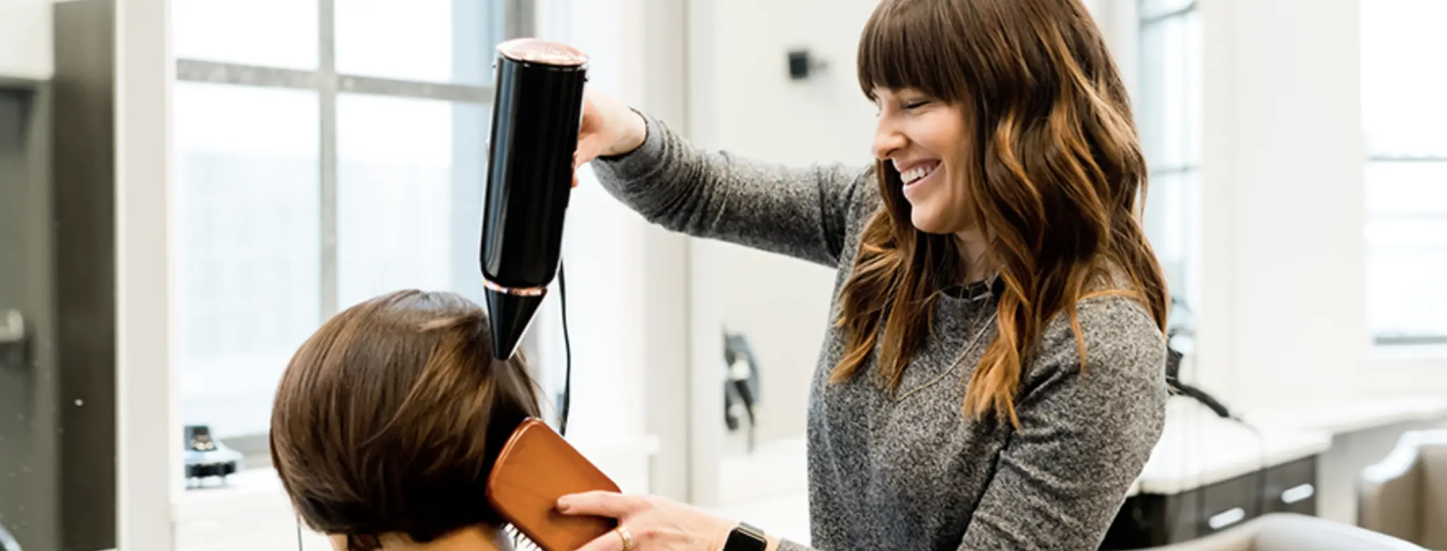female hair stylist blow drying hair in salon
