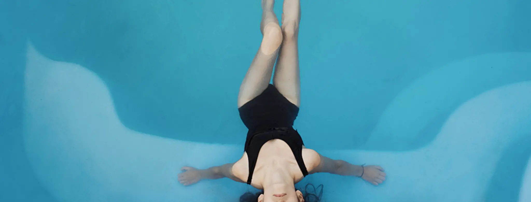 woman in black bathing suit in pool float spa