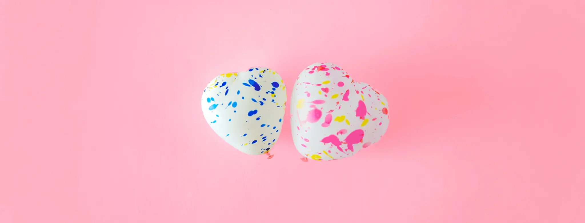 two balloon hearts on pink background