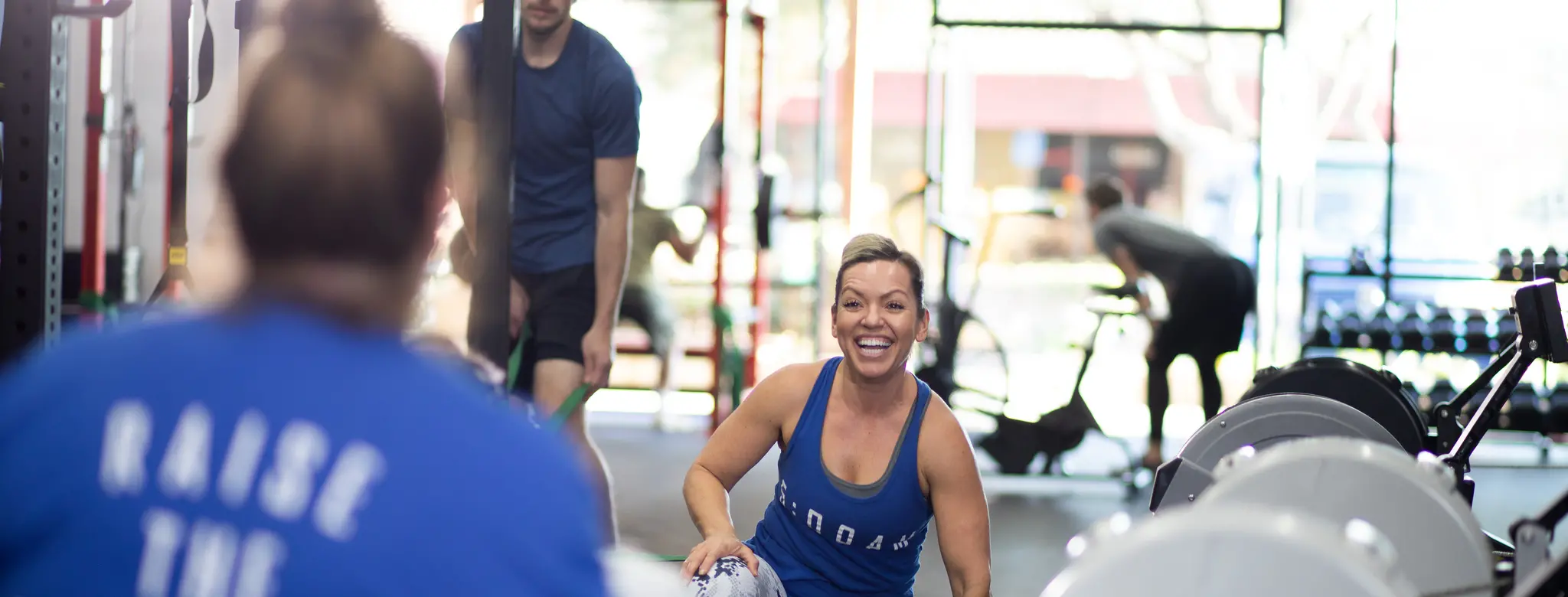 woman smiling and man working out in gym