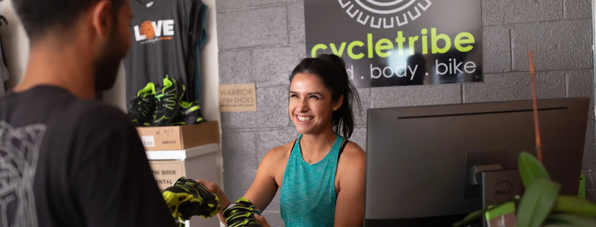 Woman at front desk helps man check into Cycletribe studio.