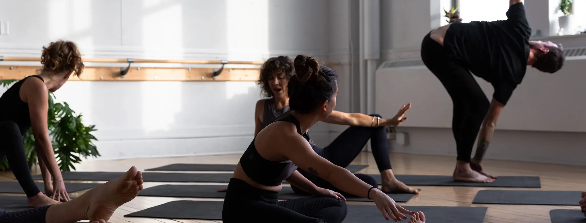 Yoga students stretch in a sunny studio before class