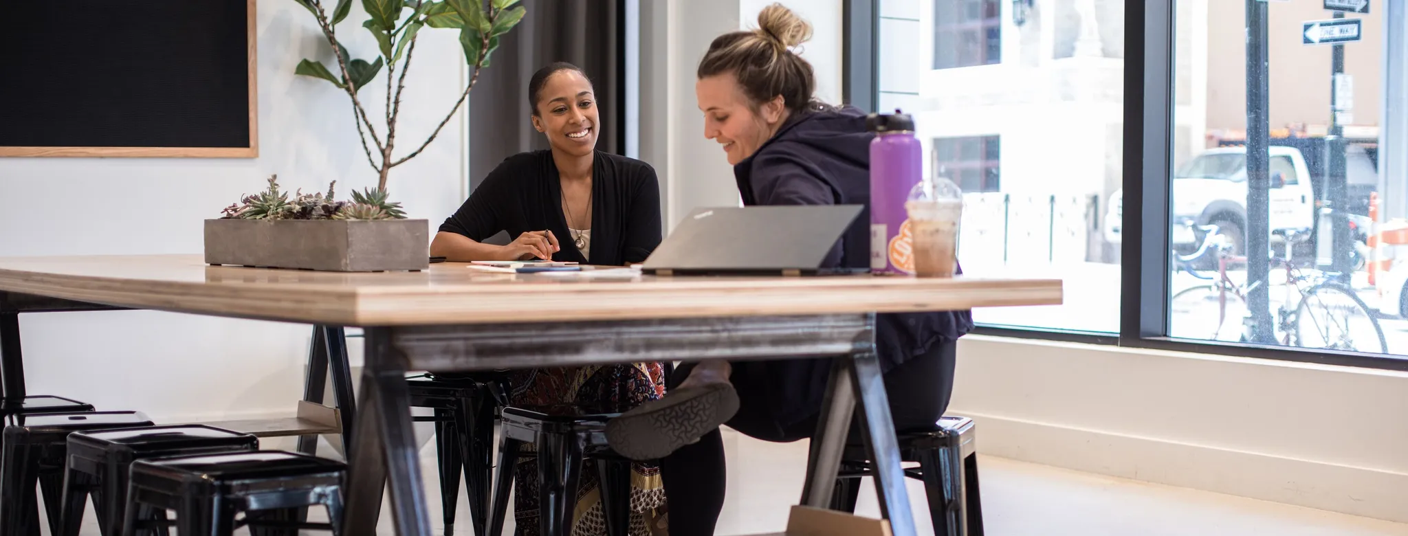 Two women sit at desk discussing business