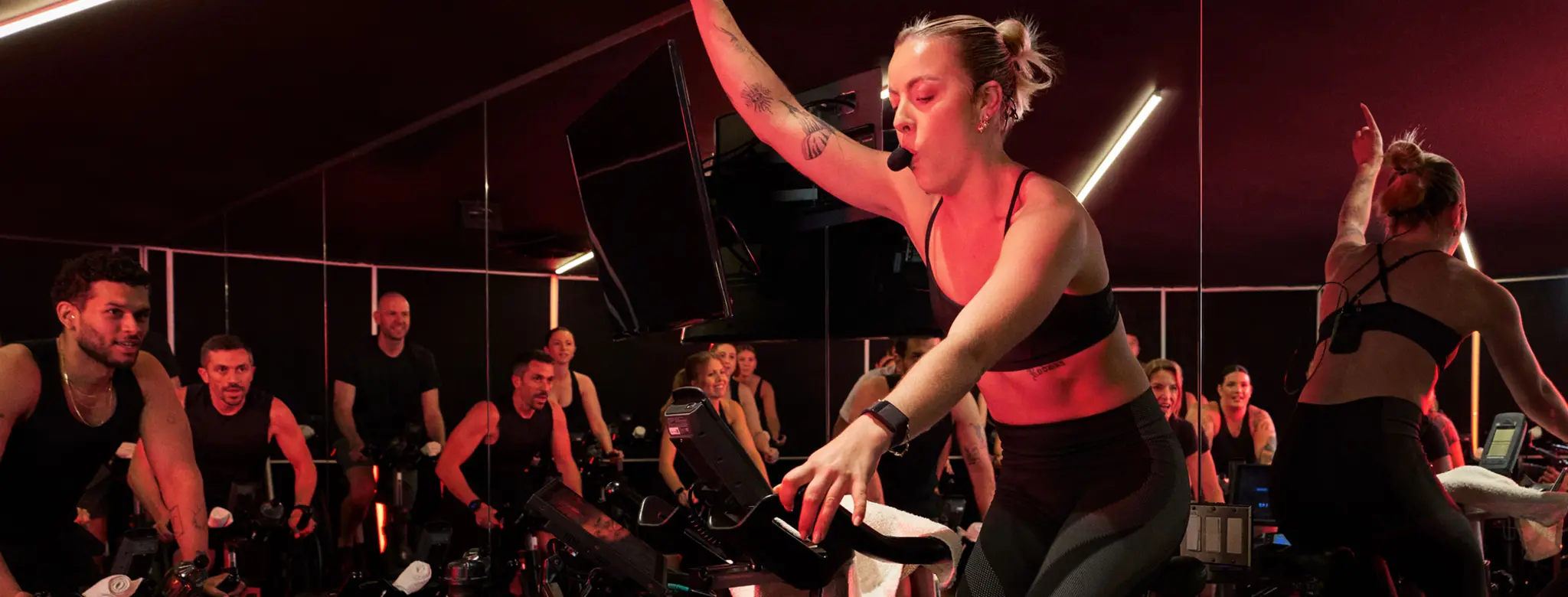 woman teaching full cycling class energetically with arm raised