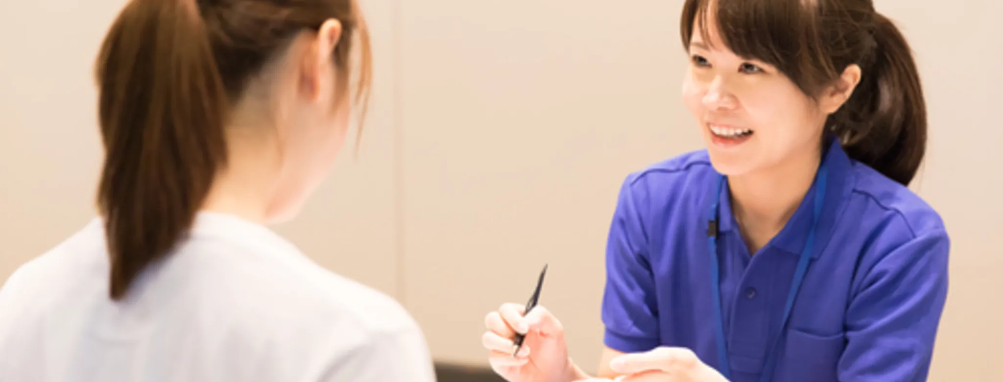 Woman in blue shirt at gym front desk showing AI assistant to client in white shirt