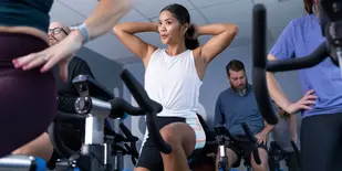 Woman adjusts her hair while working out in a cycling class
