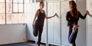 Two women stretching in a locker room