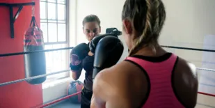 Person boxing with trainer in gym