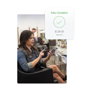 Client in salon chair using mobile device to complete salon transaction