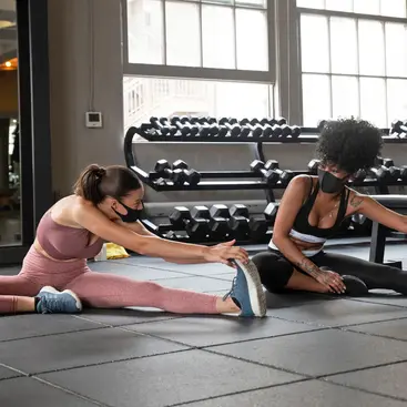 Two women stretching on gym floor